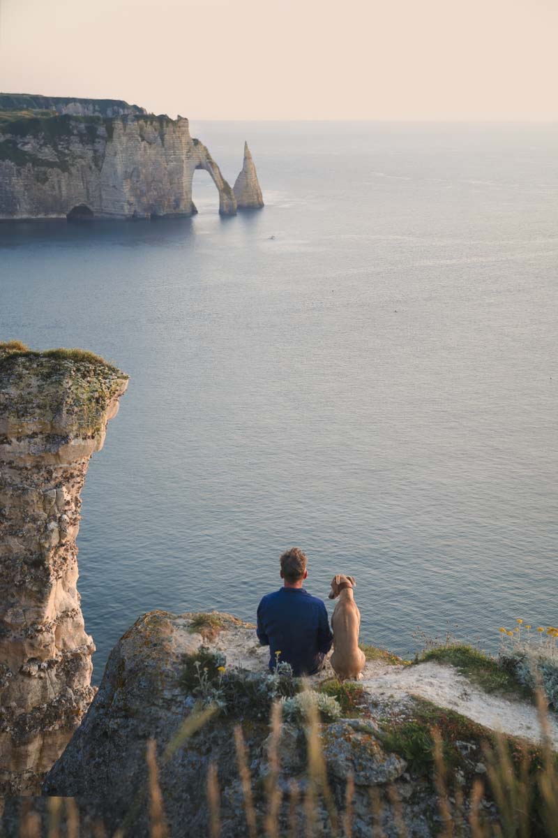 Tierfotograf Clemens Schneider mit seinem Hund Niels auf einer Klippe am Meer